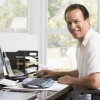 Man in home office at computer smiling