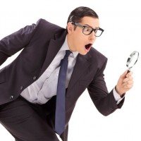 Sneaky businessman looking through a magnifying glass